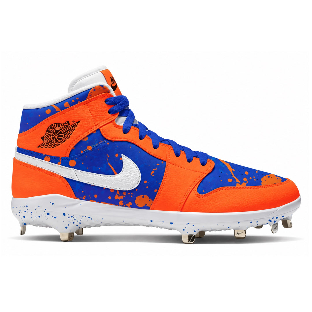 A Nike high-top baseball cleat in vibrant orange and royal blue with white accents, featuring a paint splatter design and the classic Jumpman logo on the side.