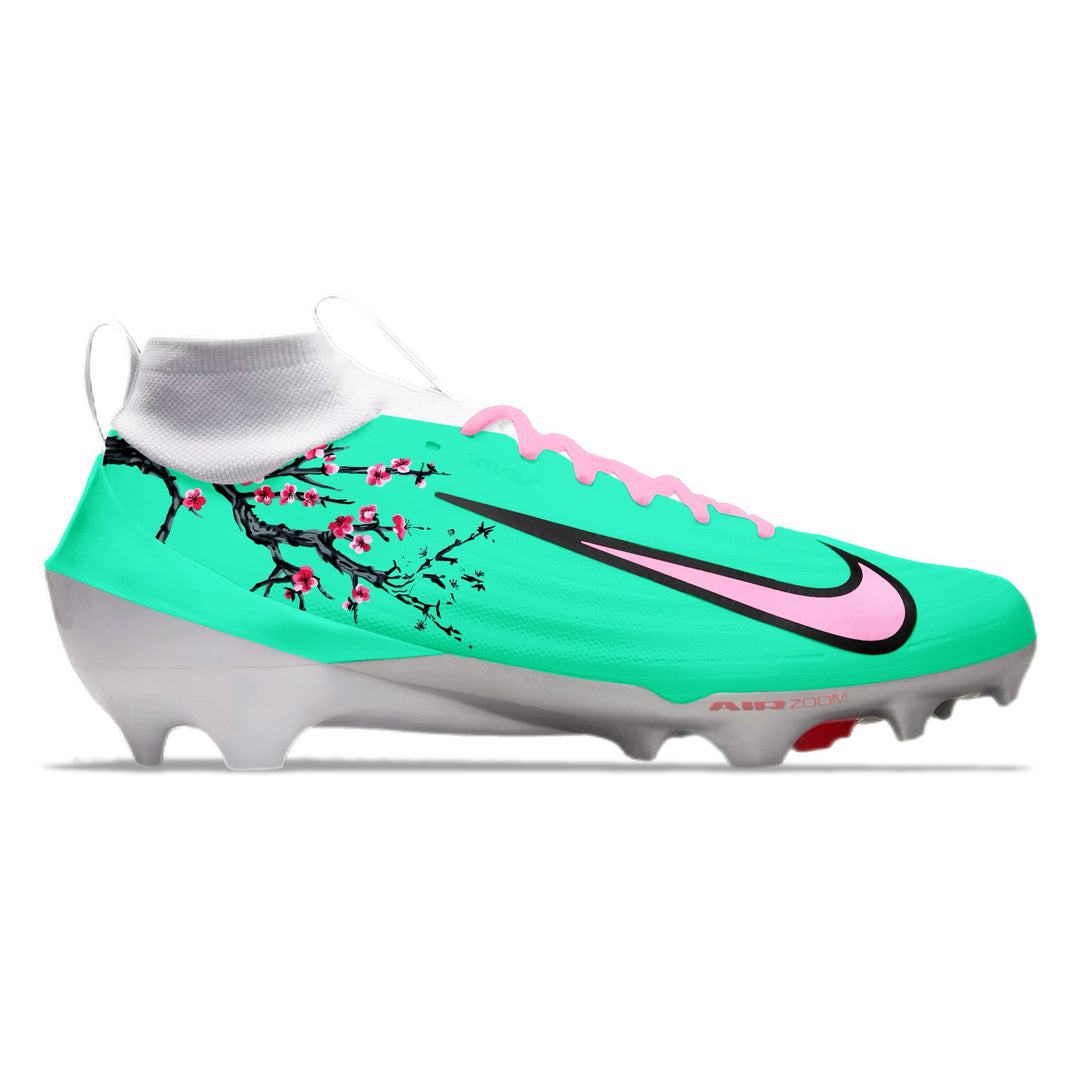 Turquoise football cleat with pink and black design on a white background.