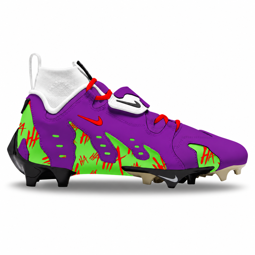 A Nike football cleat featuring a vibrant purple and neon green color-blocked design with red scratch-like accents, a white Nike swoosh on the strap, and black studs.