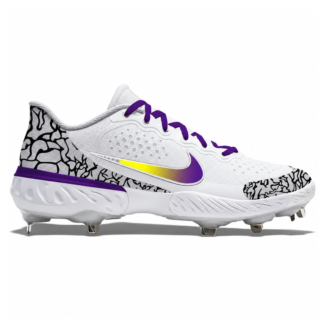 A Nike baseball cleat in white with purple laces and a purple gradient Swoosh, featuring a black and white crackle pattern on the heel and toe, and a metallic gold-to-purple gradient accent on the side.