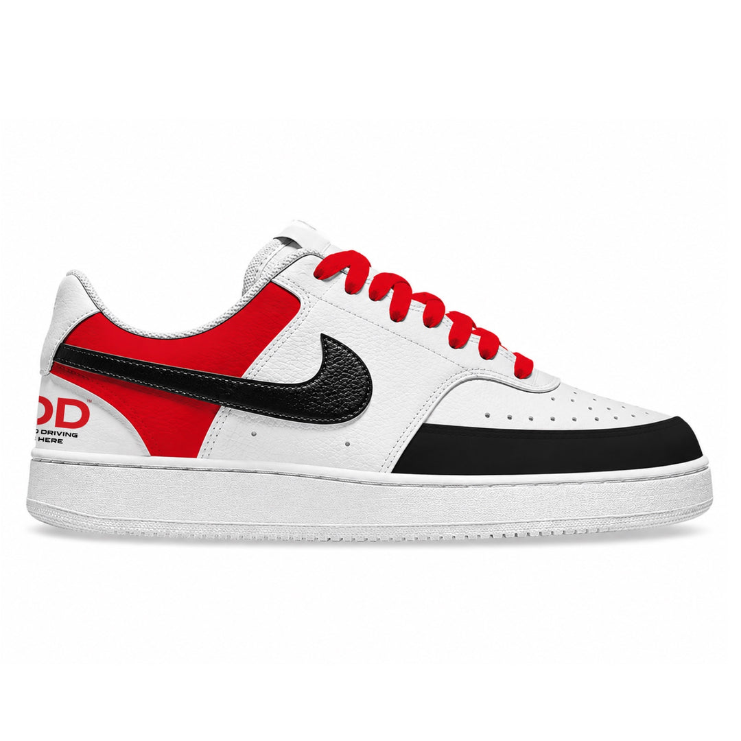 A low-top Nike sneaker in white, red, and black, featuring a white leather base, a red heel panel, a black Swoosh, red laces, and a black toe box, shown against a plain white background.