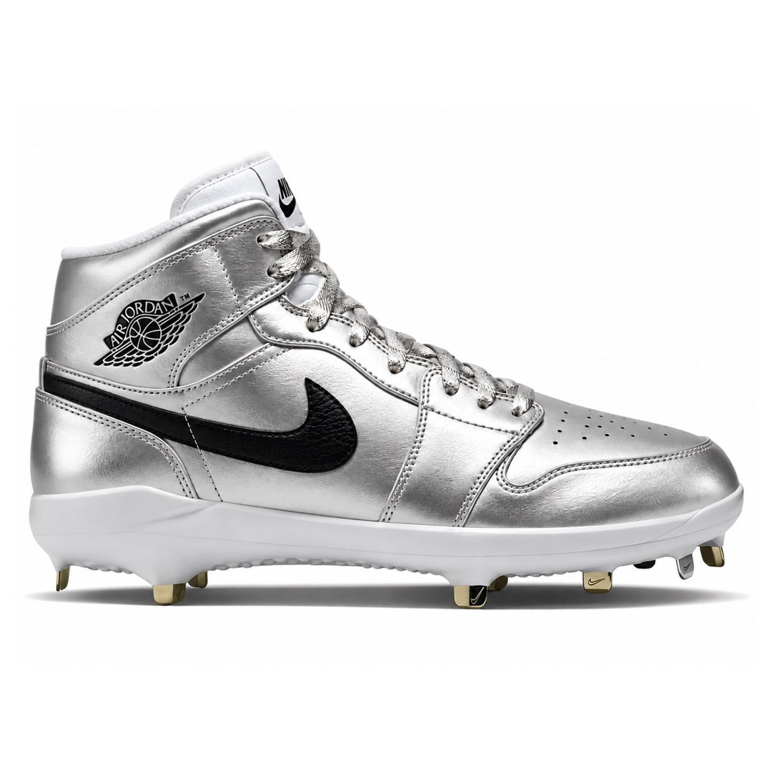 A metallic silver high-top baseball cleat featuring a black Nike Swoosh and a black embroidered Jordan Wings logo on the side, with a white midsole and gold-colored studs.