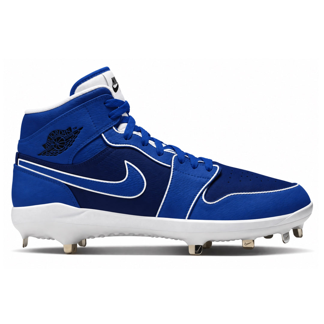 A Nike high-top baseball cleat in royal blue and white, featuring a black Jordan Wings logo on the ankle, white stitching, and metal cleats on a white midsole.