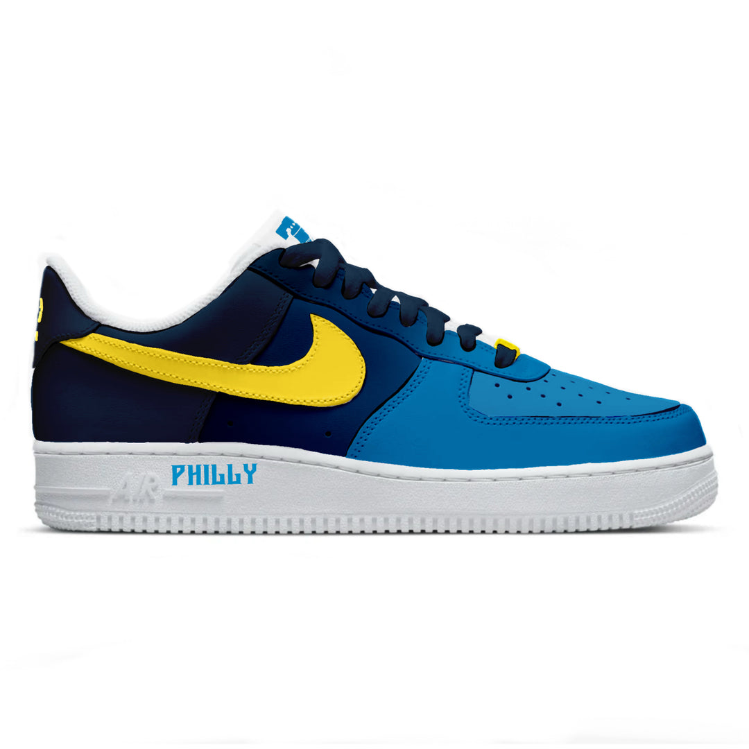 Blue and navy sneaker with yellow swoosh logo on a white background