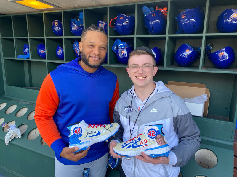 Robinson Cano and sck designer Ari holding Jackie Robinson day cleats in Philadelphia dugout.