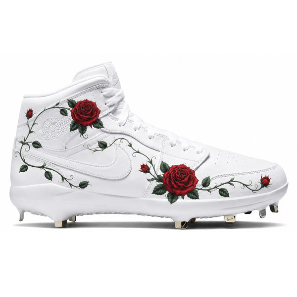 Custom white Jordan 1 Retro cleats featuring hand-painted red roses and vine detailing with spikes — by Stadium Custom Kicks