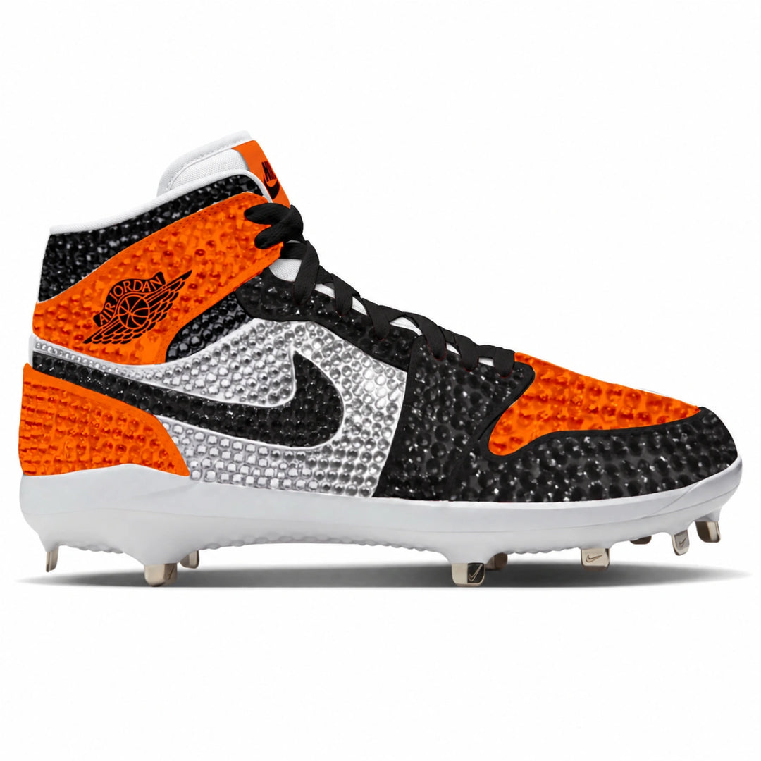 A high-top baseball cleat featuring a black and bright orange textured upper, a large silver rhinestone Nike Swoosh, a black Nike Air Jordan logo on the side, and a white sole with metal studs.