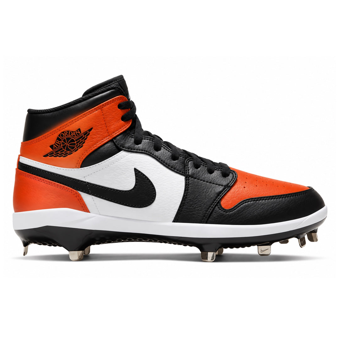 A high-top baseball cleat from the Nike Jordan line, featuring a black leather and white leather upper with vibrant orange overlays on the toe, heel, and collar. The shoe has a black Swoosh on the side, a black Jumpman logo on the heel, black laces, and metal studs on the sole.
