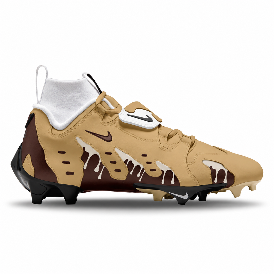 A Nike football cleat in a beige and brown color way with a dripping chocolate design, featuring a white Nike swoosh on the strap and a white Nike logo on the side, set against a plain white background.