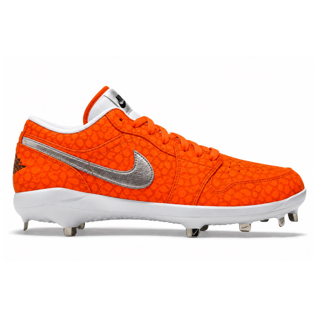 Jordan baseball cleat in vibrant orange with a textured crocodile pattern, featuring a metallic silver swoosh and white sole with metal studs, shown from a side profile on a white background.